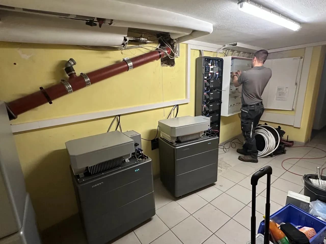 Techniker installiert Energieverteilungssystem und Batteriespeicher im Technikraum eines Gebäudes